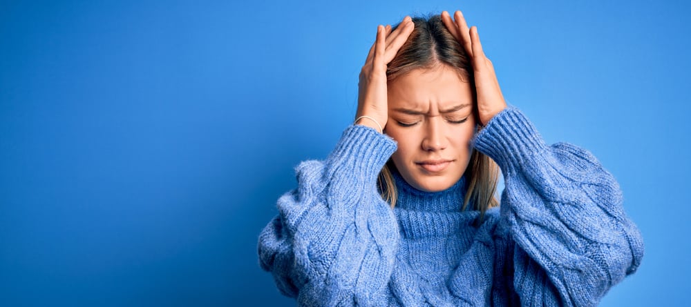 A woman grabs her head with her hands