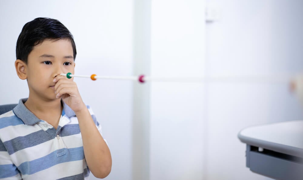 A young child is performing a Brock String Test