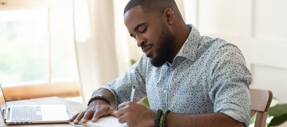 A man journaling and taking note of his own thoughts and behaviors. 