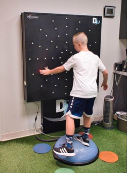 A patient balances on a Bosu ball while use the Dynavision board. 