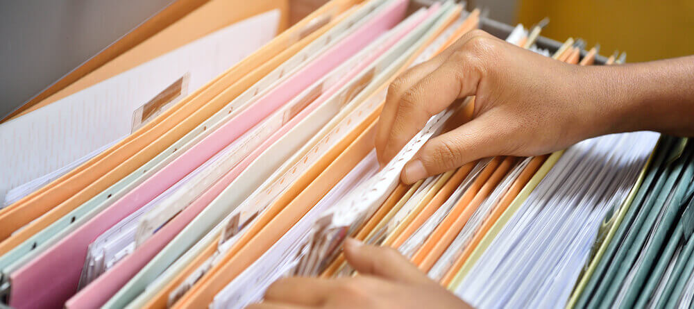 Image of someone pulling documents out of a filing cabinet