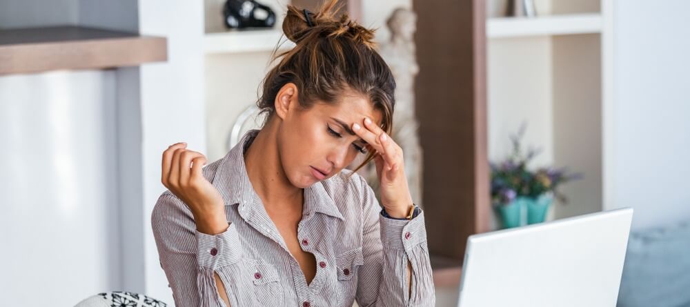A women feeling a headache as part of her post concussion symptoms.