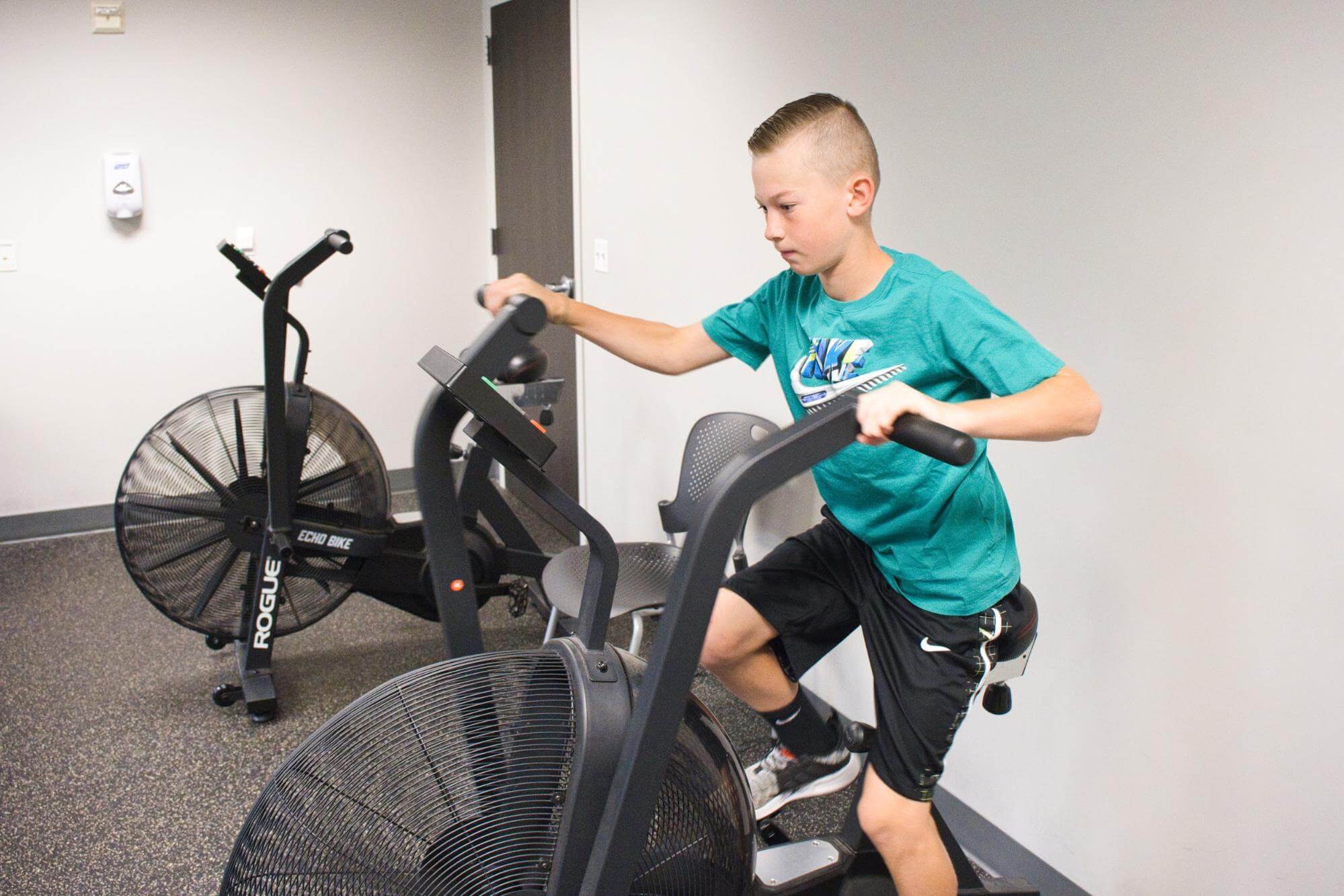 A young man uses a stationary bike machine. 