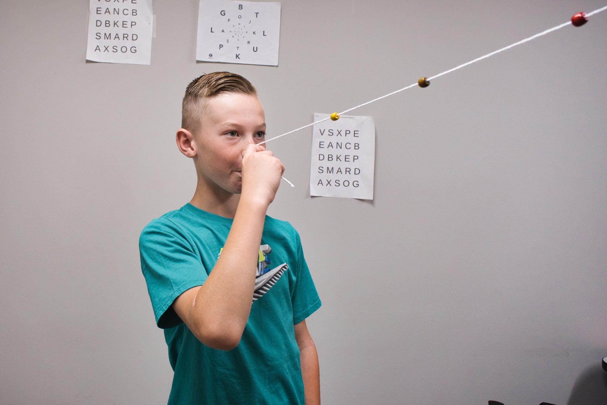 A young man demonstrates a vision therapy exercise. 