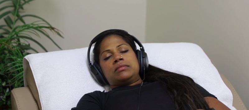 A woman at Cognitive FX lying down in a chair with headphones on. 