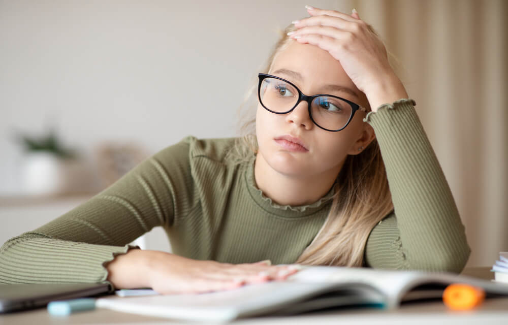 A young girl has her head in her hand while studying.