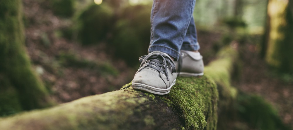 Close up of feet balancing on a log. 