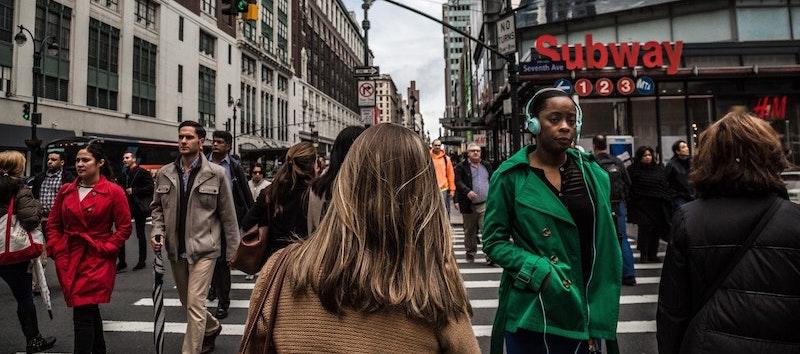 A photo of several people walking down a busy street in New York.