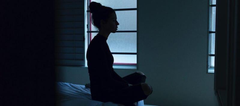 A woman who was unable to sleep sits on her bed.