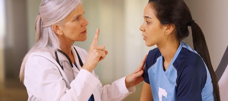 A doctor is helping her client with an eye test after a sports concussion.