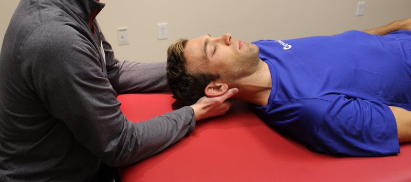 A photo of a man getting his neck adjusted on a massage table.