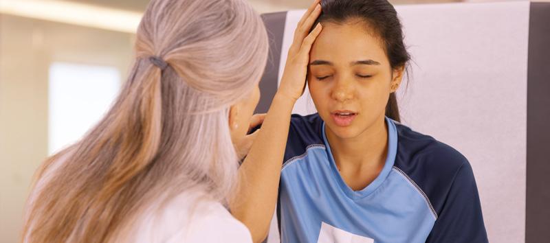 Are your symptoms from concussions, attention deficit hyperactivity disorder, or both? Learn how to obtain a diagnosis and mitigate symptoms here. (Photo shows a young girl in pain grabbing her head with one of her hands while an older woman is trying to help her.)