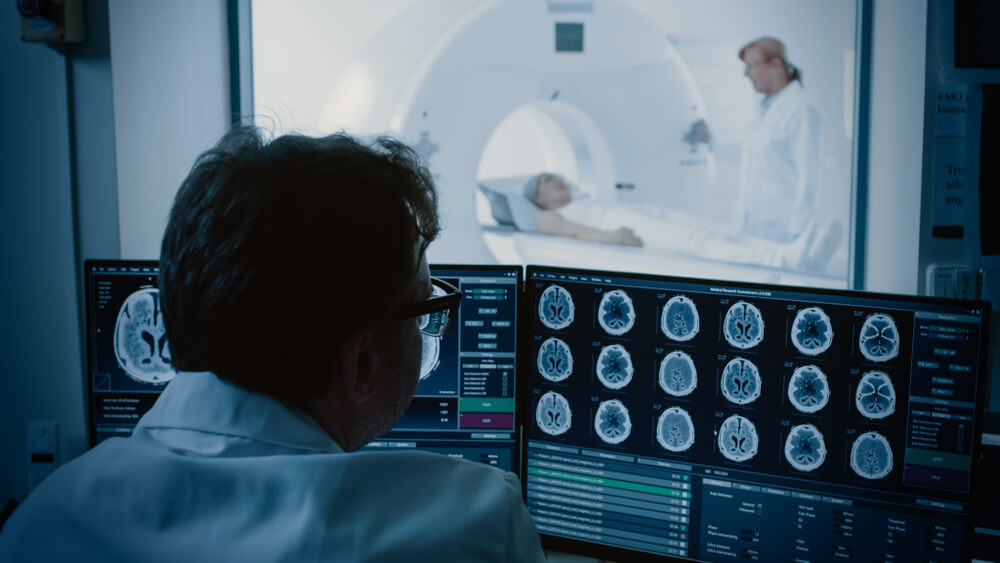 A patient getting a CT scan while the doctor looks at the imaging.