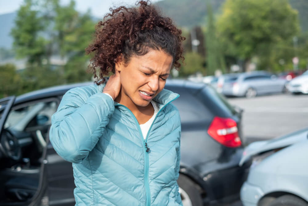 A woman holds her neck in pain.