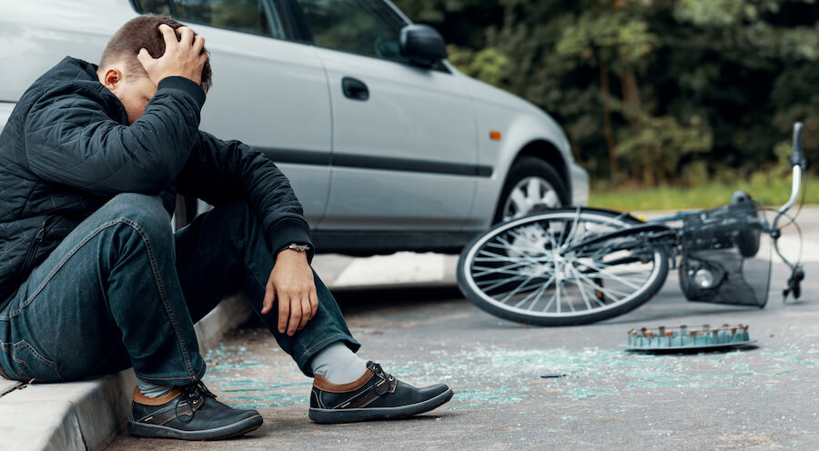 A photo of a man sitting on the ground after getting into an accident and hitting his head.