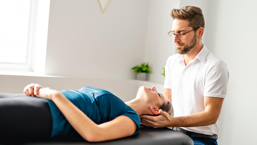 A woman is lying on a table while getting a neck adjustment