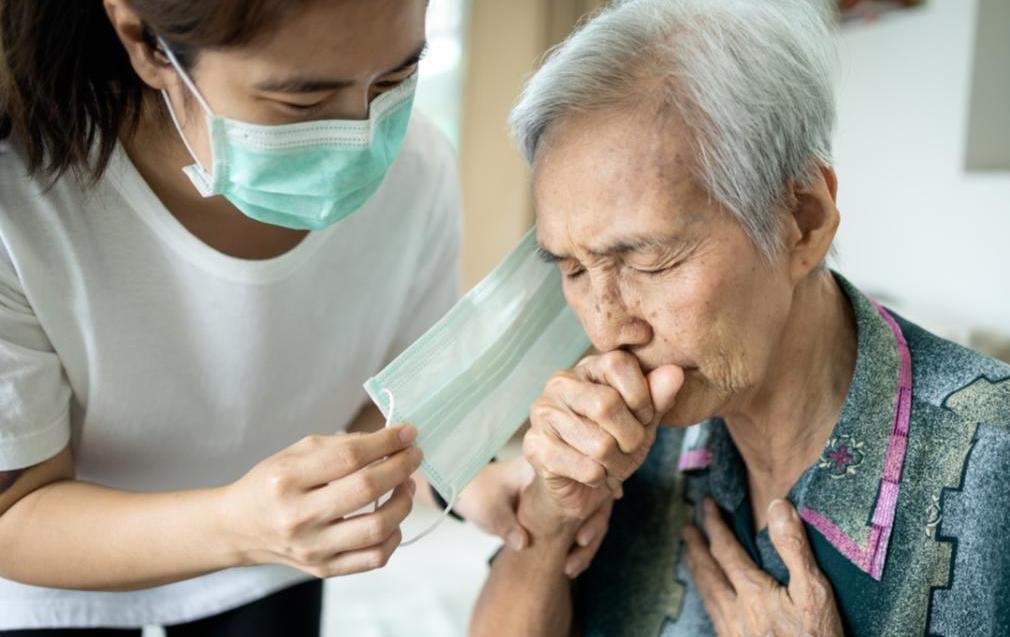 An older gentleman is having trouble catching his breath as he coughs.