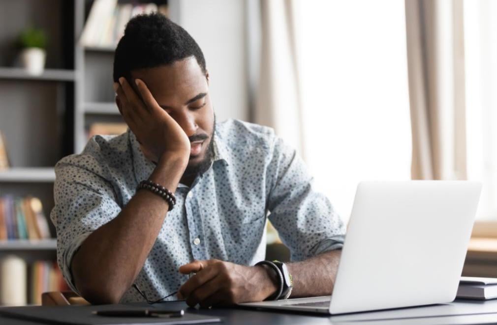 A man sits at his desk with his head in his hand.