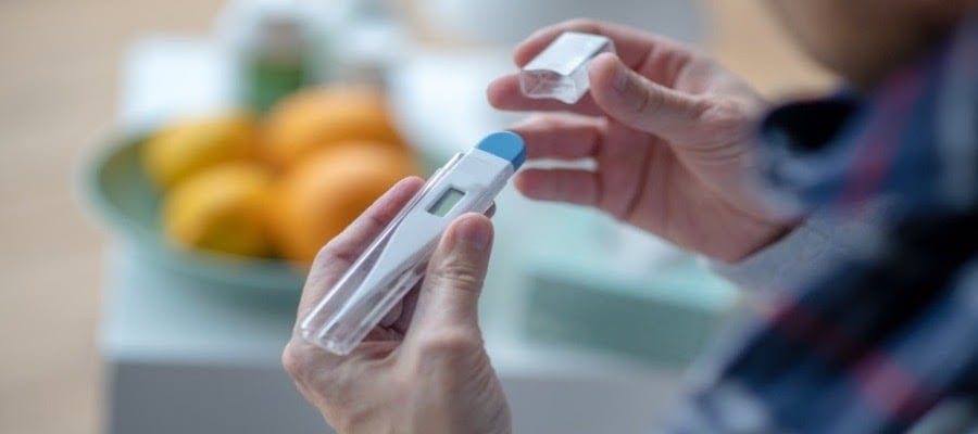 Image of person holding a thermometer. 