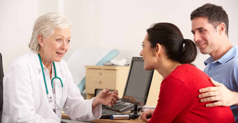 A doctor meets with a client and her husband to go over treatment options. 