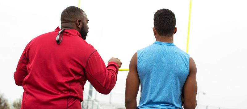 A high school football coach is giving advice to one of his players. 