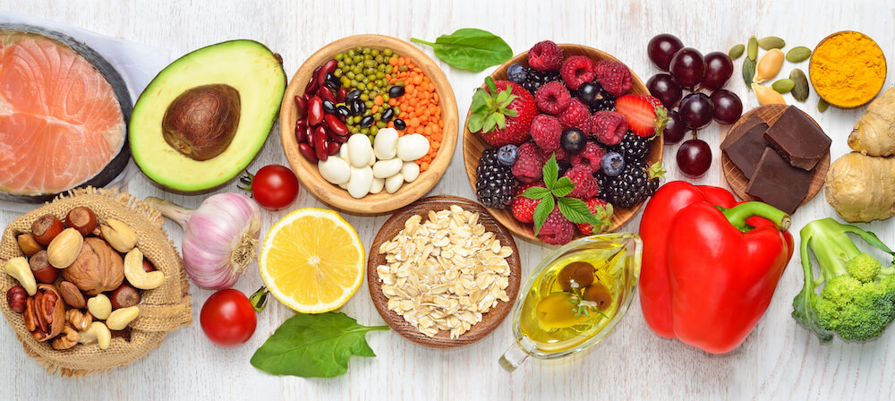 A table with a spread of healthy foods (including fruits, vegetables, whole grains, nuts, salmon).