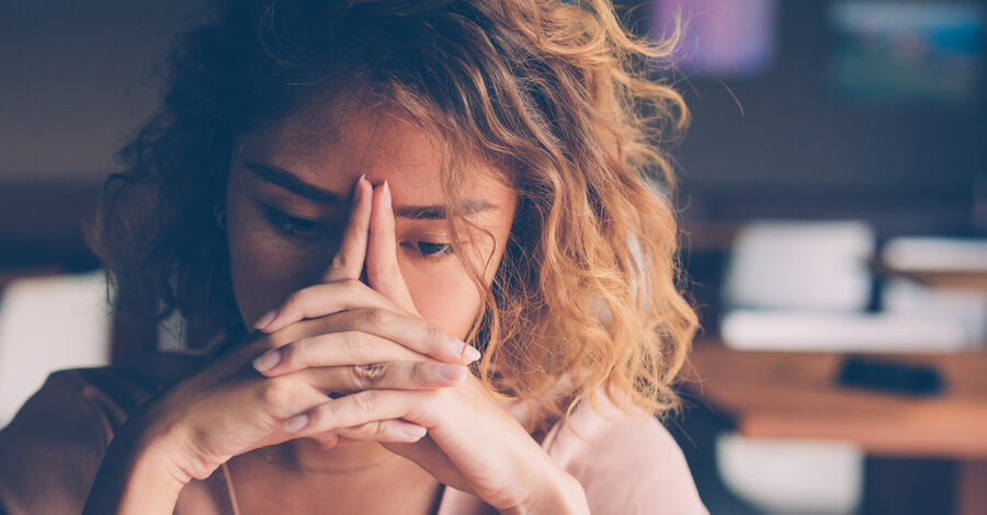 A woman overwhelmed with her hands on her face