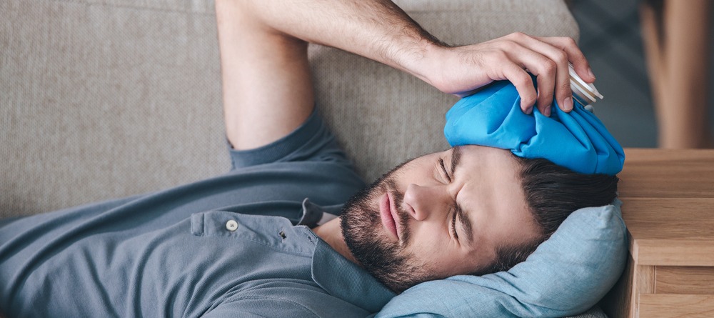 Man putting an ice pack on his head. 