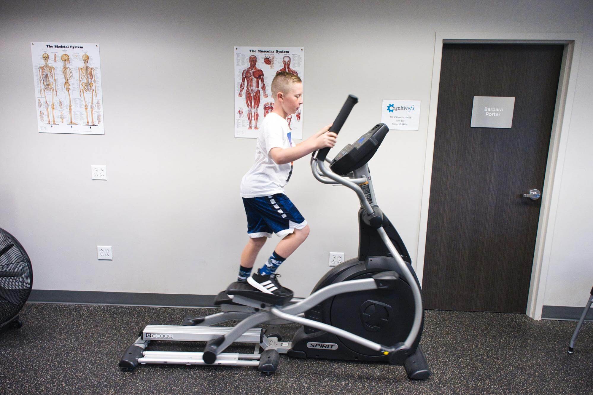 A young boy exercises on an elliptical. 
