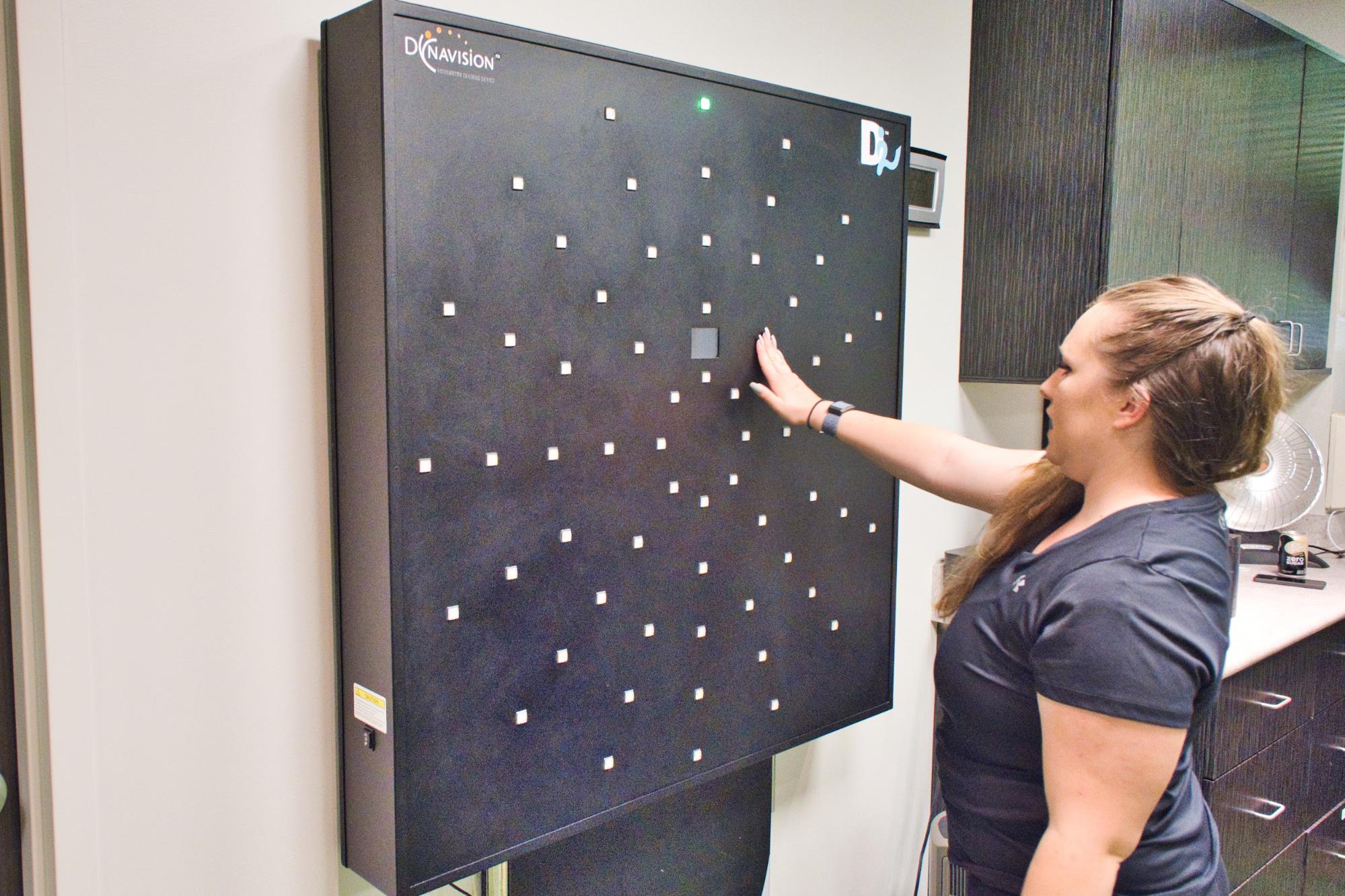 A therapist demonstrates using the Dynavision board, which challenges patients’ reaction times.