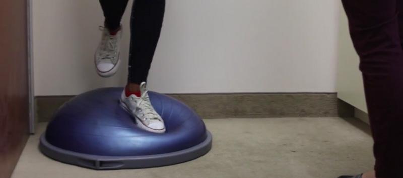 A woman standing on an exercise ball.