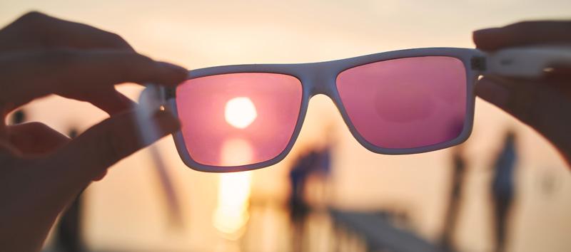 A photo of colored glasses as the sun is setting in the background.