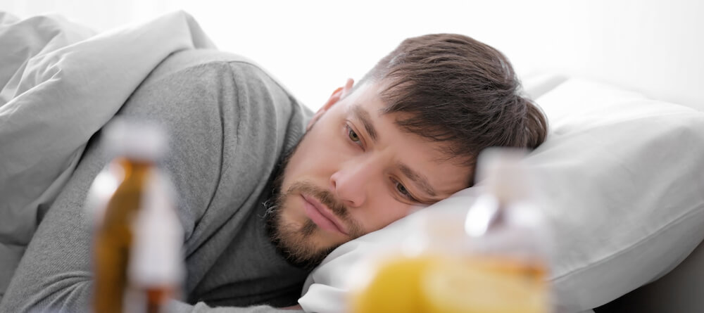 A man is lying in bed staring at the wall.