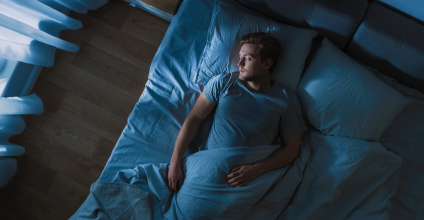 A photo of a man sleeping in his bed