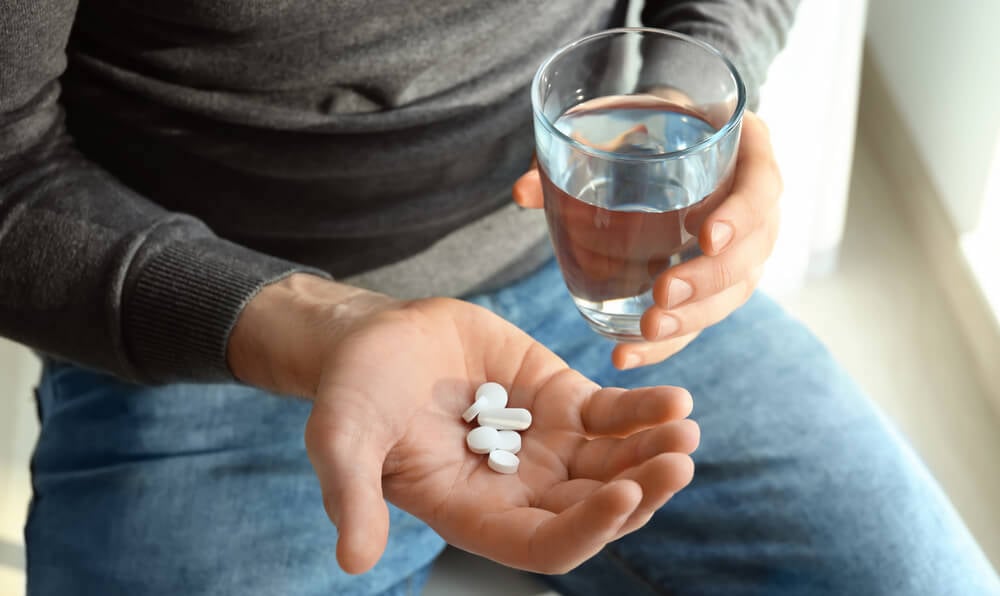 A man takes his medicine with a glass of water