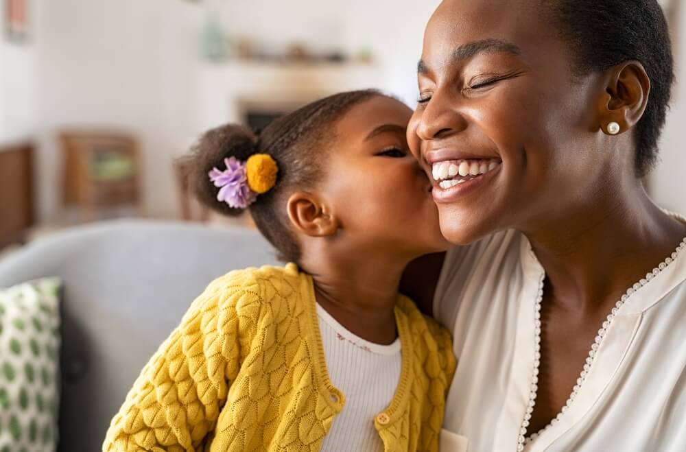 A little girl kisses her mom's cheek