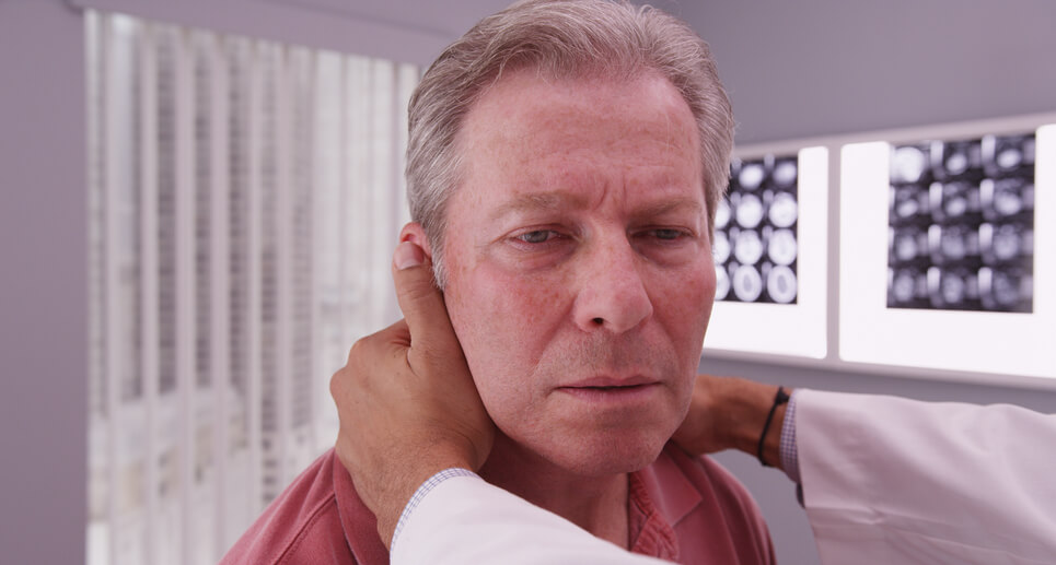 A patient having his neck examined by his doctor