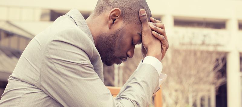 Post concussion brain fog can be caused by a number of issues. Read this post to learn more about them, plus what you can do to feel better. (In this photo, a man is sitting down with his head in his hands.)