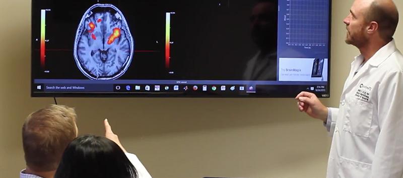 A Cognitive FX doctor goes over an fMRI scan with his patient.