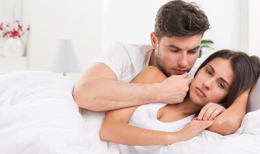 A man comforting a sad woman in bed