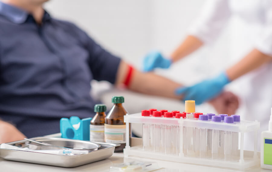 A man is sitting down while getting blood drawn.