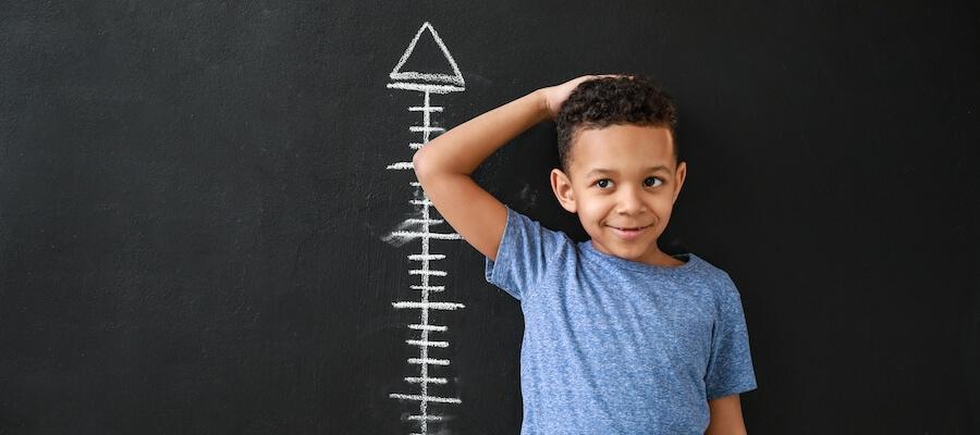 A young boy is standing against a wall to get his height taken.