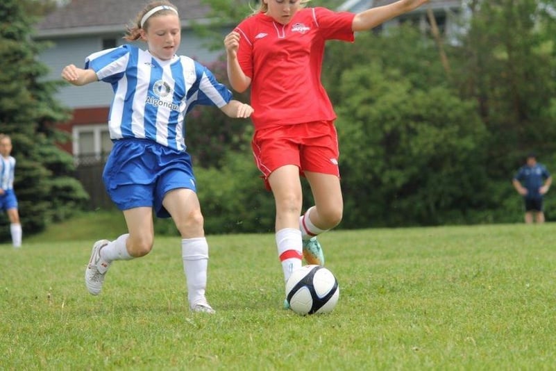 A photo of Sam kicking the soccer ball in the middle of a game.