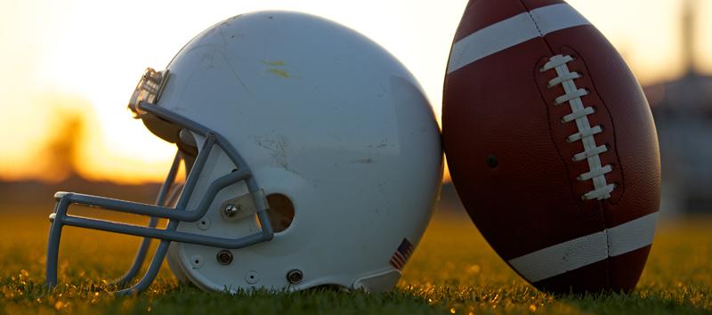 A football helmet sitting next to a football.