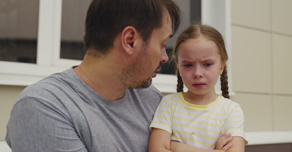 A little girl is talking to her dad after having a temper tantrum