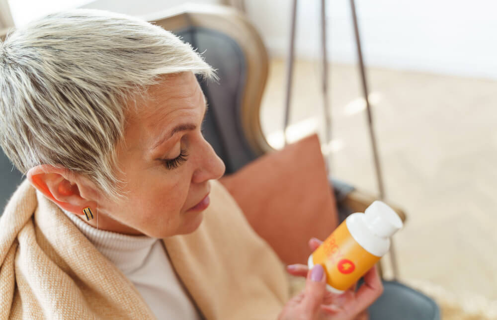 A woman is reading the label on her medication bottle.