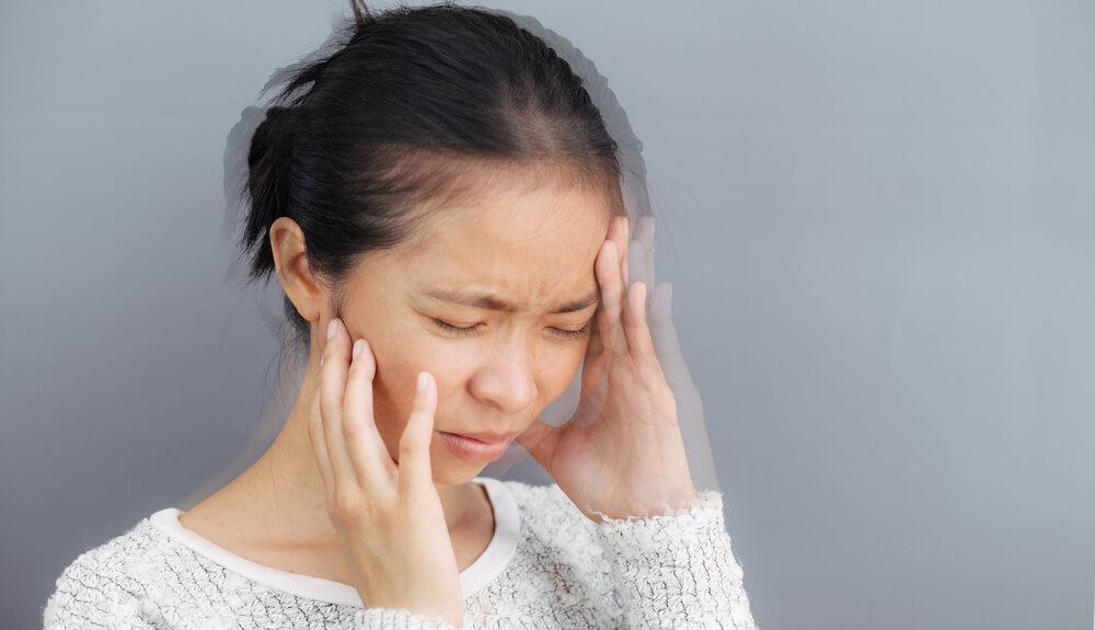 woman with vertigo holding her face