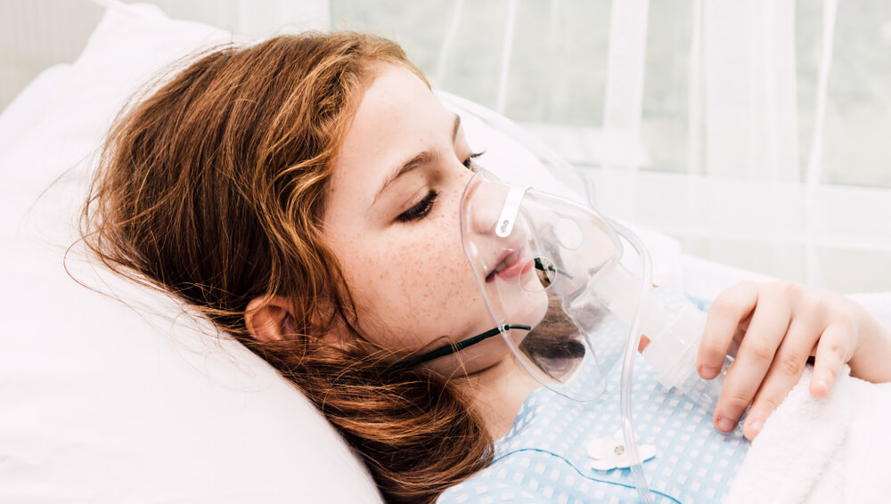 A young girl in the hospital with an oxygen mask. (There is effective treatment for the long-term effects of carbon monoxide poisoning; learn more here.)