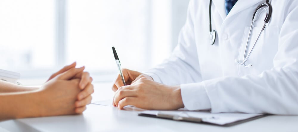 A photo showing a doctor and his patient sitting down during a consultation.